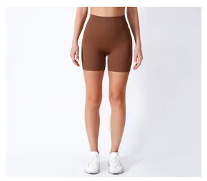 Detailed view of high waisted ribbed yoga shorts in dark brown on model in white studio