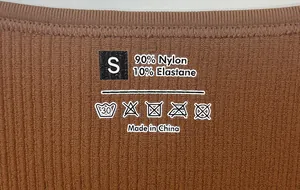 Detail of printed care label showing S size and 90% nylon fabric on brown ribbed bodysuit
