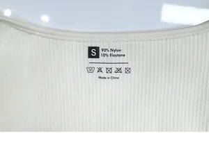 Detailed view of neckline and printed size S label on ribbed cream yoga bodysuit fabric