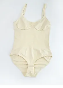 Detail view of beige seamless bodysuit showing tummy control texture and bottom hook closure