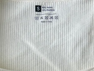 Detail of ribbed knit fabric on seamless jumpsuit showing 90% nylon and 10% elastane label