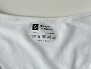 Detail of printed care label on white seamless yoga bodysuit showing S size and fabric