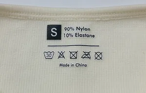 Macro shot of product label on ribbed yoga bodysuit showing size S and material blend