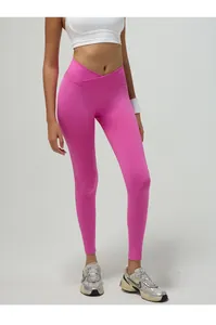 Dettaglio della vita a V incrociata e cucitura push-up sui leggings da yoga rosa acceso