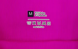 Nahaufnahme des Pflegeetiketts Größe M auf rosa nahtlosen Leggings mit Materialmix