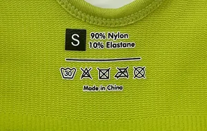 Close-up of printed label on green yoga bodysuit showing S size and fabric composition