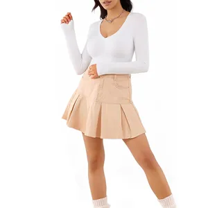 Women's white V-neck long sleeve bodysuit paired with a pleated khaki mini skirt