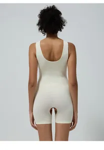 Rear view of beige seamless bodysuit showing U-shaped open back and ribbed knit texture