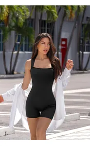 Outdoor street shot of black ribbed yoga jumpsuit with square neck and white cardigan