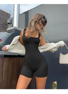 Close-up of black ribbed seamless romper paired with a white sherpa jacket and handbag