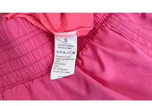 Primer plano de etiqueta S en pantalones rosas con 92% poliéster y 8% elastano de tejido