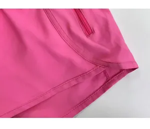 Detalle de pantalones cortos de yoga rosa con bolsillo de cremallera y dobladillo curvo