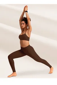 Detail shot of cross-back yoga bra with slim straps and high-waist matte brown leggings