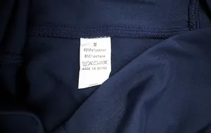 Detail view of garment care label on navy yoga pants showing size M and fabric composition