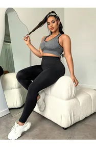Detalle de los leggings de yoga negros de talle alto y el sujetador deportivo gris en modelo