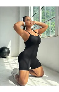 Close-up of black plus size yoga jumpsuit with cross back straps in a bright gym setting