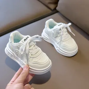 Detailed view of white kids' sneakers featuring flower-embossed soles and premium synthetic leather