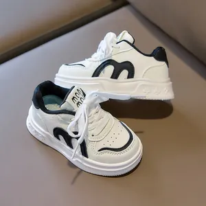 Detail view of children's white sneakers with black M letter and poker pattern sole