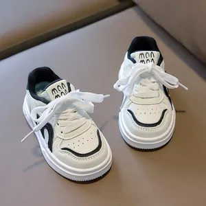 Detailed top view of kids sneakers featuring white leather, black piping, and soft rubber soles