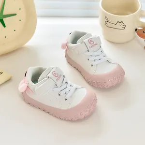 Détail de chaussures bébé rose et blanc avec scratch et décoration boule en peluche