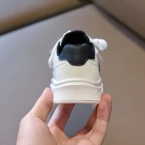 Detail of children's white leather sneakers showing black collar trim and soft thick sole