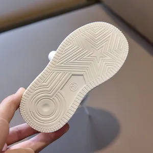 Close-up of non-slip white rubber sole for kids sneakers featuring star patterns and size 23