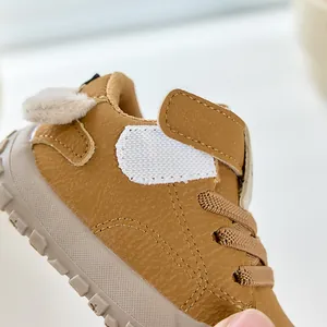 Vue détaillée de chaussures pour bébés en cuir marron avec velcro et pompons décoratifs