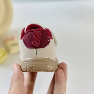 Vue détaillée du talon en cuir beige et de la languette bordeaux des chaussures bébé