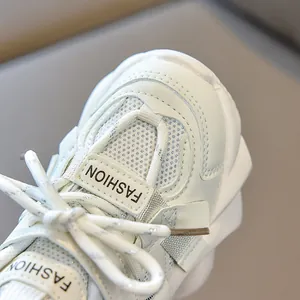 Close-up of white children's sneakers with mesh texture and silver-threaded laces