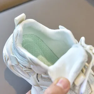 Detail view of children white mesh sneakers showing green insoles and thick foam padding