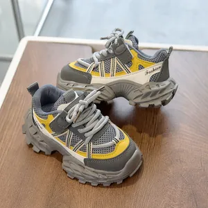 Detail view of children's sneakers with gray mesh, yellow accents, and anti-slip rubber soles