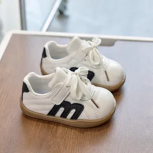 Detalle de zapatillas infantiles de cuero blanco con logo M negro y suela de goma