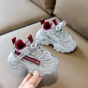 Detailed view of silver mesh kids' sneakers with hook-and-loop strap on leather sofa