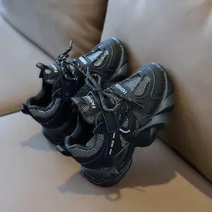 Detail view of breathable black kids sneakers with thick anti-slip wavy rubber soles