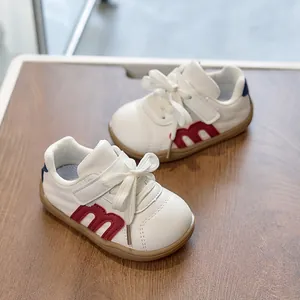 Detalle de zapatilla infantil de cuero blanco con logo M rojo y suela de goma