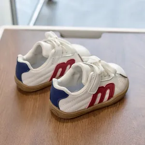 Detalle de zapatillas infantiles con parche M rojo y cierre de velcro ajustable