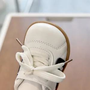 Vista superior de zapatillas de cuero blanco para niños con rayas negras y cordones
