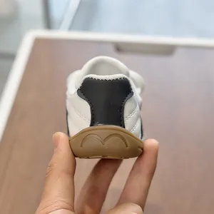 Detalle de zapatilla infantil con suela de goma marrón y diseño de talón en forma de M