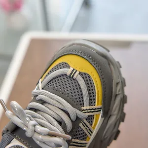 Detail of dark grey kids sneaker featuring breathable mesh and yellow leather trim