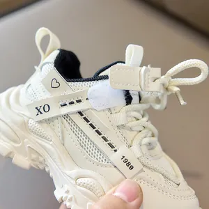 Detail shot of cream kid sneakers with mesh panels and heart print on cross straps