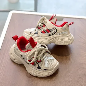 Detail of kids' cream sneakers featuring red accents, breathable mesh, and hook-and-loop straps