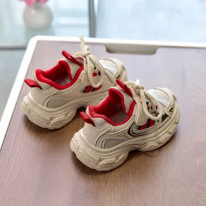 Detail view of cream kids chunky sneakers with red accents on a wooden background