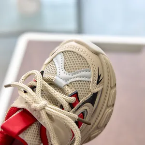 Detail view of children's fashion sneaker showing beige mesh texture and red accents
