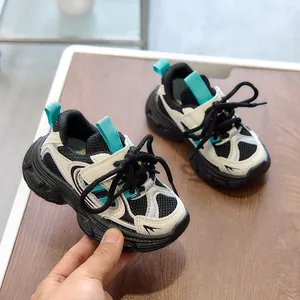 Detail view of children's chunky sneakers with mesh upper and green accents on wood base