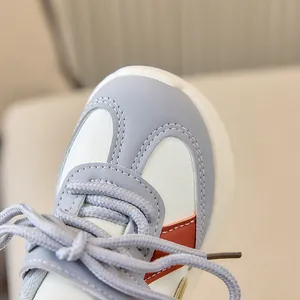 Détail de basket enfant gris blanc et orange montrant coutures et lacets tissés