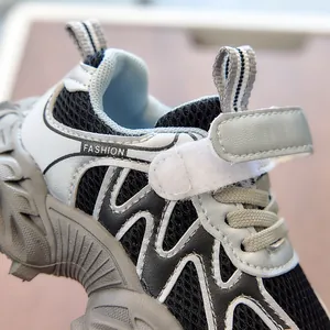 Detail of children sneakers showing breathable black mesh with velcro strap and grey accents