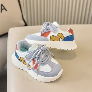 Vue détaillée des baskets blanches pour enfants avec patchwork bleu et broderie M