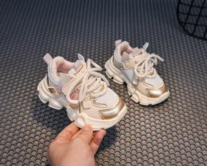 Detail showing the pink mesh upper and gold metallic accents of the kids sports sneaker