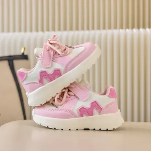 Détail de baskets sportives pour enfants en rose et blanc avec décoration M en relief