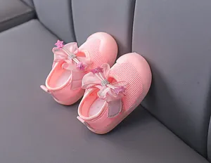 Close-up of baby girl pink mesh shoes featuring a large bow and star-shaped sequins detail
